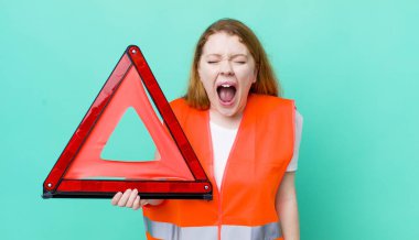 Kızıl saçlı, güzel bir kadın agresif bir şekilde bağırıyor, çok kızgın görünüyor. Araba üçgeni kazası.