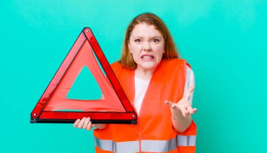 Kızıl saçlı, güzel bir kadın sinirli, sinirli ve sinirli görünüyor. Araba üçgeni kazası.