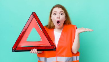 Kızıl saçlı, güzel bir kadın şaşırmış ve şok olmuş görünüyor. Çenesi düşmüş, elinde bir nesne var. Araba üçgeni kazası.