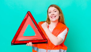 Kızıl saçlı güzel bir kadın kendini mutlu hissediyor ve bir meydan okumayla yüzleşiyor ya da kutluyor. Araba üçgeni kazası.