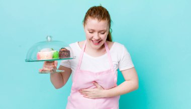 Kızıl saçlı güzel bir kadın komik bir şakaya yüksek sesle gülüyor. Ev yapımı kek konsepti