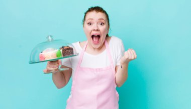 Kızıl saçlı güzel kadın şok olmuş hissediyor, gülüyor ve başarıyı kutluyor. Ev yapımı kek konsepti