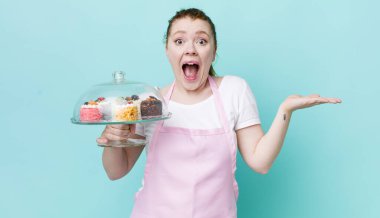 Kızıl saçlı güzel kadın kendini mutlu hissediyor ve inanılmaz bir şeye hayret ediyor. Ev yapımı kek konsepti