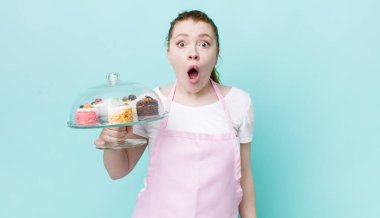 Kızıl saçlı güzel kadın çok şaşırmış ya da şaşkın görünüyor. Ev yapımı kek konsepti