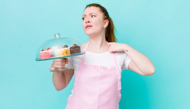 Kızıl saçlı güzel kadın stresli, endişeli, yorgun ve hayal kırıklığına uğramış hissediyor. Ev yapımı kek konsepti