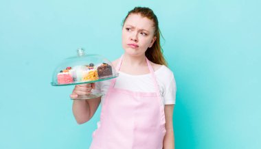 Kızıl saçlı, güzel bir kadın üzgün, üzgün ya da kızgın ve yana bakıyor. Ev yapımı kek konsepti