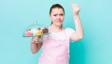 Kızıl saçlı, güzel bir kadın kapiş ya da para hareketi yapıyor, sana ödemeni söylüyor. Ev yapımı kek konsepti