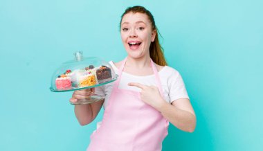 Kızıl saçlı, güzel bir kadın heyecanlı ve şaşırmış görünüyor. Ev yapımı kek konsepti