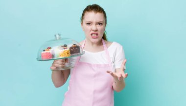 Kızıl saçlı, güzel bir kadın sinirli, sinirli ve sinirli görünüyor. Ev yapımı kek konsepti