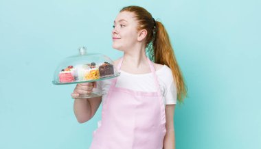 Profil bakışlı kızıl saçlı güzel kadın hayal mi kuruyor yoksa hayal mi kuruyor? Ev yapımı kek konsepti