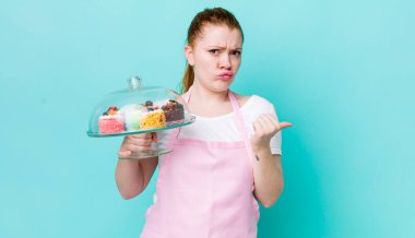 Kızıl saçlı, güzel bir kadın inançsızlıktan şaşkın şaşkın bakıyor. Ev yapımı kek konsepti