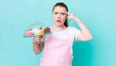 Kızıl saçlı güzel kadın şaşırmış görünüyor, yeni bir düşünce, fikir ya da konsept fark ediyor. Ev yapımı kek konsepti