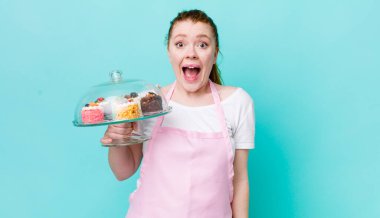 Kızıl saçlı güzel kadın mutlu ve hoş bir şekilde şaşırmış görünüyor. Ev yapımı kek konsepti