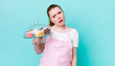 Kızıl saçlı güzel kadın şaşkın ve şaşkın hissediyor. Ev yapımı kek konsepti