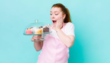 Kızıl saçlı güzel kadın mutlu, heyecanlı ve şaşırmış hissediyor. Ev yapımı kek konsepti