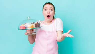 Kızıl saçlı güzel kadın çok şaşırmış ve şok olmuş hissediyor. Ev yapımı kek konsepti