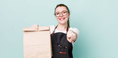 Kızıl saçlı güzel kadın kamerayı işaret ederek seni seçiyor. teslimat kavramını kaldır