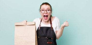 Kızıl saçlı güzel kadın şok olmuş hissediyor, gülüyor ve başarıyı kutluyor. teslimat kavramını kaldır