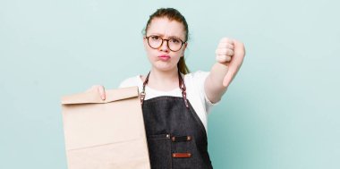 Kızıl saçlı, güzel bir kadın kendini kötü hissediyor, baş parmağını kaldırıyor. teslimat kavramını kaldır