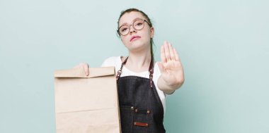 Kızıl saçlı güzel kadın ciddi görünüyor. Avuç içini gösteriyor. Durdurma hareketi yapıyor. teslimat kavramını kaldır