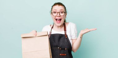 Kızıl saçlı güzel kadın kendini mutlu hissediyor ve inanılmaz bir şeye hayret ediyor. teslimat kavramını kaldır