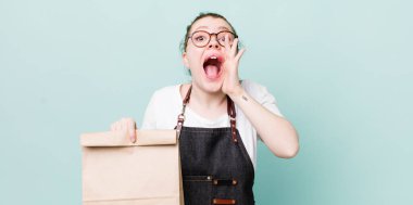 Kızıl saçlı, güzel bir kadın kendini mutlu hissediyordu. Elleri ağzının kenarında bağırıyordu. teslimat kavramını kaldır