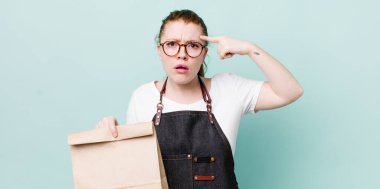 Kızıl saçlı güzel kadın kafası karışık ve şaşkın hissediyor, deli olduğunu gösteriyor. teslimat kavramını kaldır