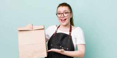 kızıl saçlı güzel bir kadın neşeli bir şekilde gülümsüyor, mutlu hissediyor ve bir konsept gösteriyor. teslimat kavramını kaldır