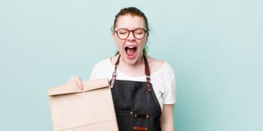 Kızıl saçlı, güzel bir kadın agresif bir şekilde bağırıyor, çok kızgın görünüyor. teslimat kavramını kaldır