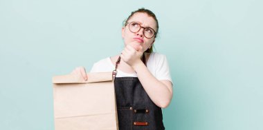 Kızıl saçlı güzel kadın düşünüyor, kuşkulu ve şaşkın hissediyor. teslimat kavramını kaldır