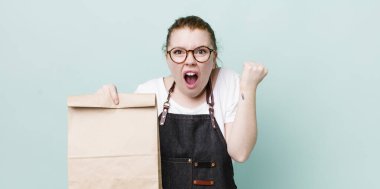 Kızıl saçlı güzel bir kadın sinirli bir ifadeyle agresif bir şekilde bağırıyor. teslimat kavramını kaldır