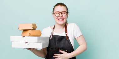 Kızıl saçlı güzel bir kadın komik bir şakaya yüksek sesle gülüyor. teslimat kavramını kaldır