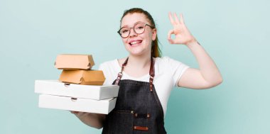 Kızıl saçlı güzel bir kadın kendini mutlu hissediyor. Onayını iyi bir hareketle gösteriyor. teslimat kavramını kaldır