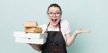 Kızıl saçlı güzel kadın kendini mutlu hissediyor ve inanılmaz bir şeye hayret ediyor. teslimat kavramını kaldır