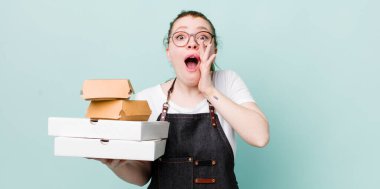 Kızıl saçlı, güzel bir kadın kendini mutlu hissediyordu. Elleri ağzının kenarında bağırıyordu. teslimat kavramını kaldır