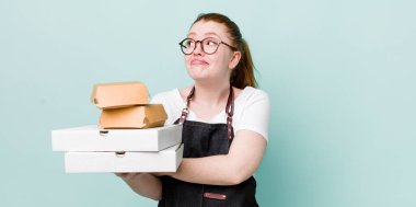 Kızıl saçlı güzel kadın omuz silkiyor, kafası karışık ve kararsız. teslimat kavramını kaldır