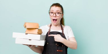 Kızıl saçlı, güzel bir kadın heyecanlı ve şaşırmış görünüyor. teslimat kavramını kaldır