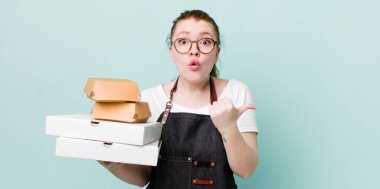 Kızıl saçlı, güzel bir kadın inançsızlıktan şaşkın şaşkın bakıyor. teslimat kavramını kaldır