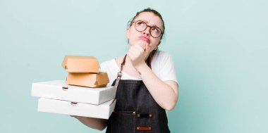 Kızıl saçlı güzel kadın düşünüyor, kuşkulu ve şaşkın hissediyor. teslimat kavramını kaldır