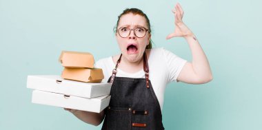 Kızıl saçlı güzel kadın ellerini havaya kaldırarak çığlık atıyor. teslimat kavramını kaldır