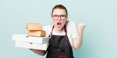 Kızıl saçlı güzel bir kadın sinirli bir ifadeyle agresif bir şekilde bağırıyor. teslimat kavramını kaldır