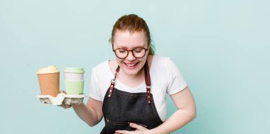 Kızıl saçlı güzel bir kadın komik bir şakaya yüksek sesle gülüyor. kahve konseptini kaldır.