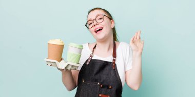 Kızıl saçlı güzel kadın mutlu bir şekilde gülümsüyor, el sallıyor, seni selamlıyor ve selamlıyor. kahve konseptini kaldır.