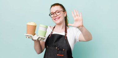 Kızıl saçlı güzel kadın gülümsüyor ve arkadaş canlısı görünüyor, beş numarayı gösteriyor. kahve konseptini kaldır.