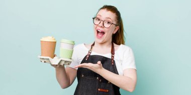 kızıl saçlı güzel bir kadın neşeli bir şekilde gülümsüyor, mutlu hissediyor ve bir konsept gösteriyor. kahve konseptini kaldır.