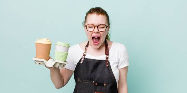 Kızıl saçlı, güzel bir kadın agresif bir şekilde bağırıyor, çok kızgın görünüyor. kahve konseptini kaldır.