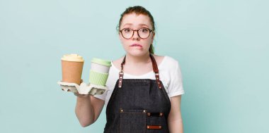 Kızıl saçlı güzel kadın kafası karışık ve şaşkın görünüyor. kahve konseptini kaldır.