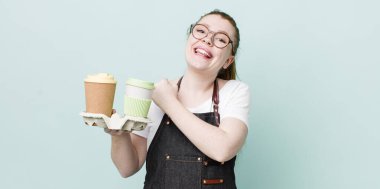 Kızıl saçlı güzel bir kadın kendini mutlu hissediyor ve bir meydan okumayla yüzleşiyor ya da kutluyor. kahve konseptini kaldır.