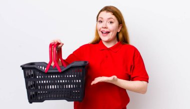 kızıl saçlı güzel bir kadın neşeli bir şekilde gülümsüyor, mutlu hissediyor ve bir konsept gösteriyor. boş alışveriş sepeti kavramı