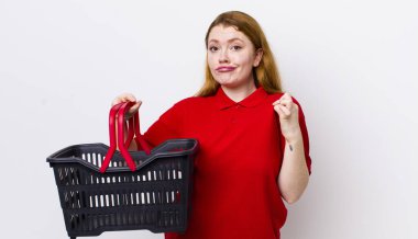 Kızıl saçlı güzel kadın kibirli, başarılı, pozitif ve gururlu görünüyor. boş alışveriş sepeti kavramı